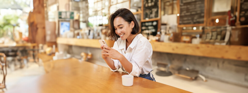 Happy customer using a phone app at a local cafe